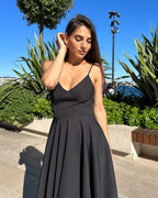 Rochie neagra eleganta scurta cu bretele, fusta evazata, femeie imbracata, fundal natural.