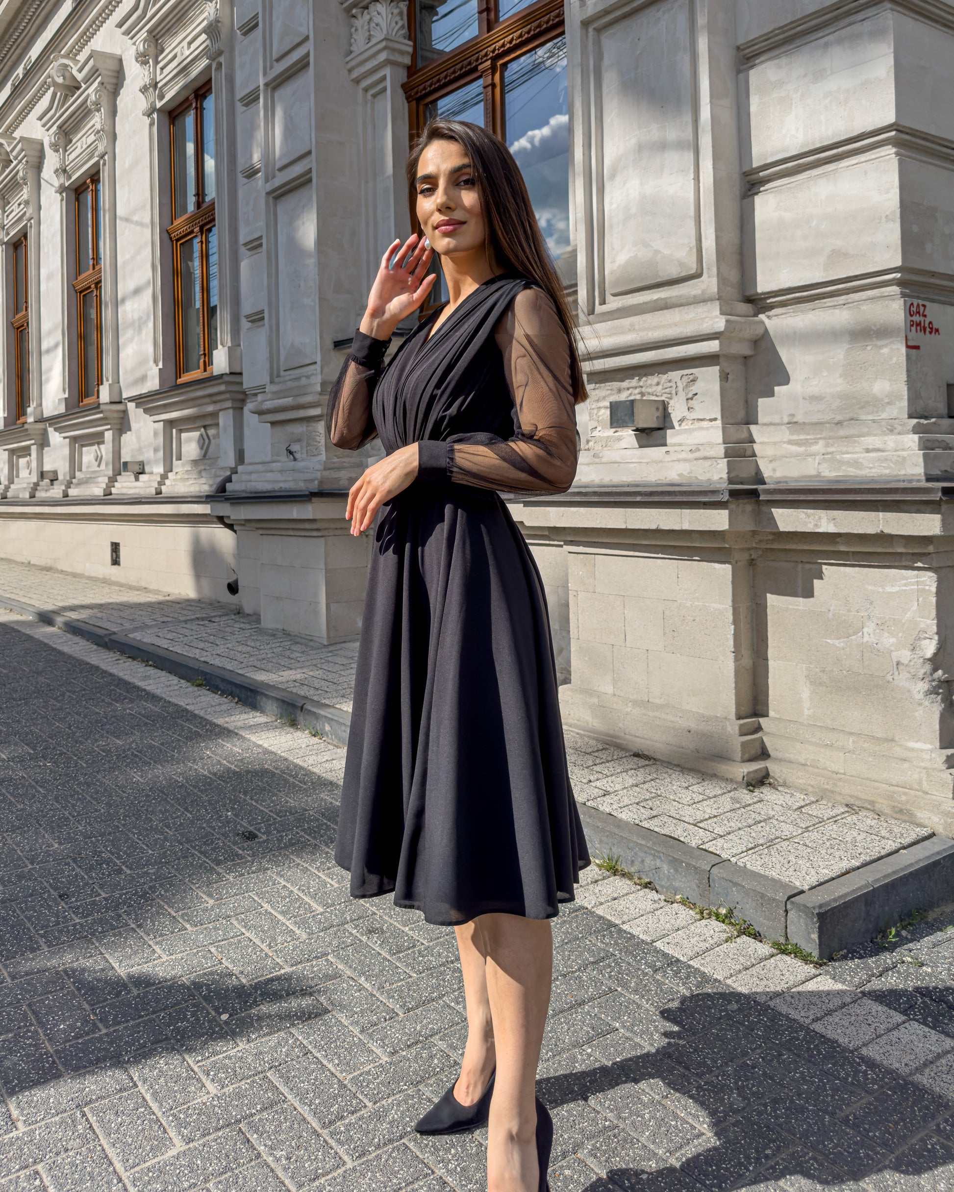 Rochie de ocazie cu mâneci lungi și decolteu în V, doamnă purtând-o în exterior.