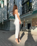 Rochie alba elegantă cu bretele și slit, lungime 108 cm, material crep elastic, potrivită pentru evenimente speciale.