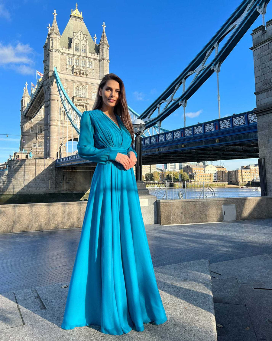Rochie de ocazie lungă din voal verde smarald, cu decolteu în V și mâneci lungi, ideală pentru evenimente elegante.